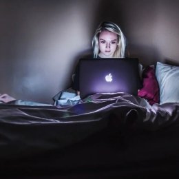 person in bed with laptop
