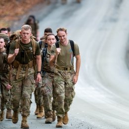 Cadets participating in the Norwich University Legacy March, marching on a road surrounded by trees and fallen leaves