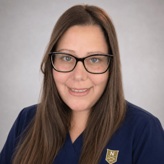 Person wearing navy Norwich University School of Nursing scrubs and glasses.