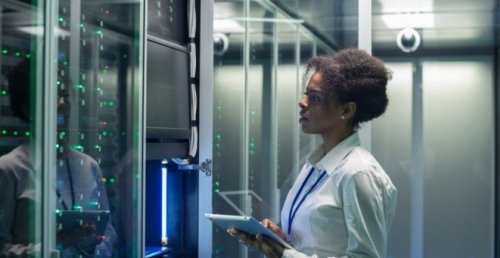 cybersecurity professional works on a tablet in a data center