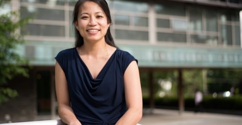 a smiling history researcher stands in front of a building