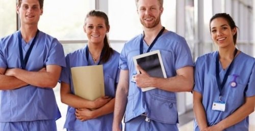 group of nurses smiling and standing in hallway