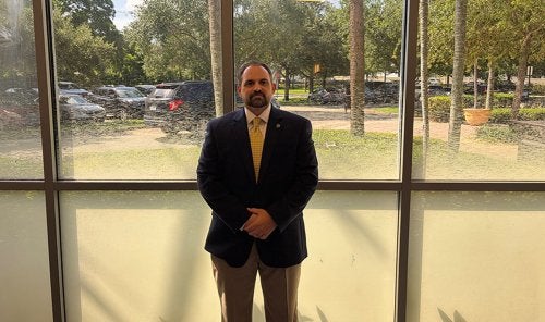 dave santos in professional attire standing in front of a window.
