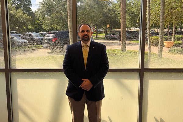 dave santos in professional attire standing in front of a window.