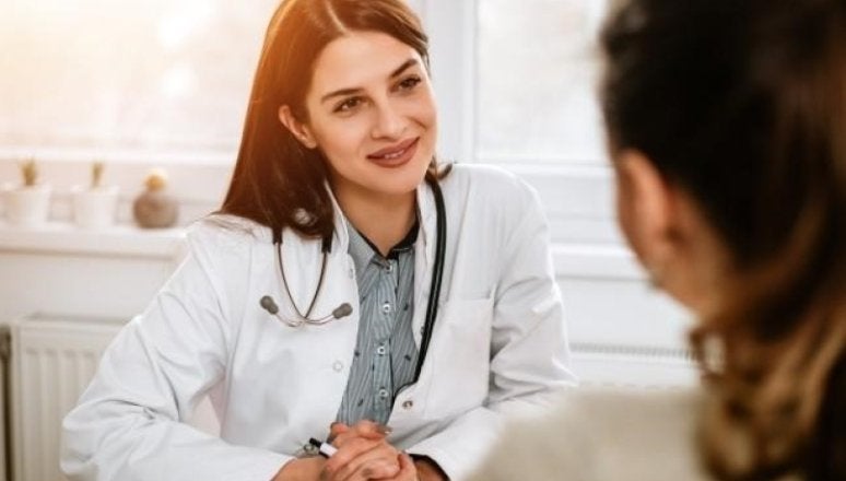 smiling nurse leader in a meeting with paperwork on their desk