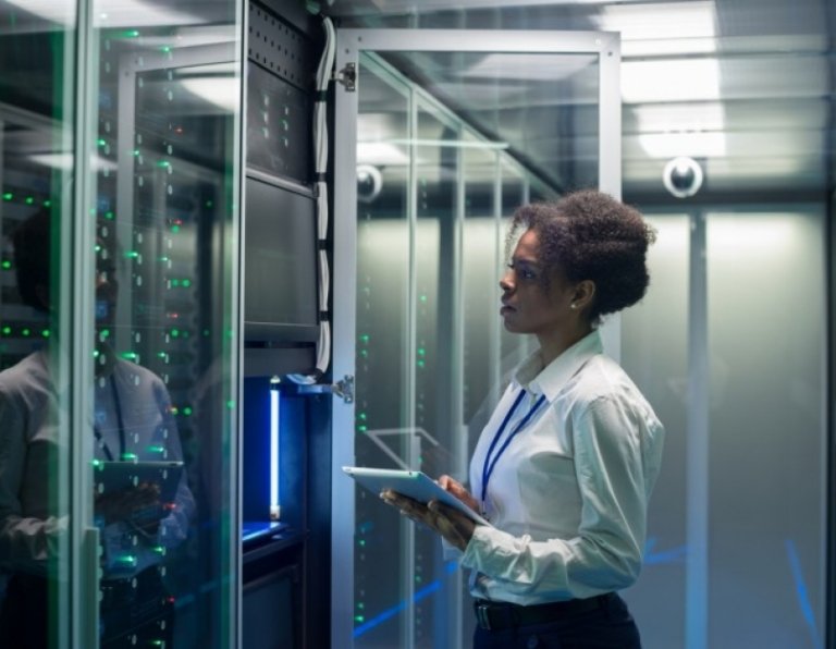 cybersecurity professional works on a tablet in a data center