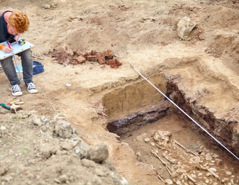 an archeologist taking notes at a dig site