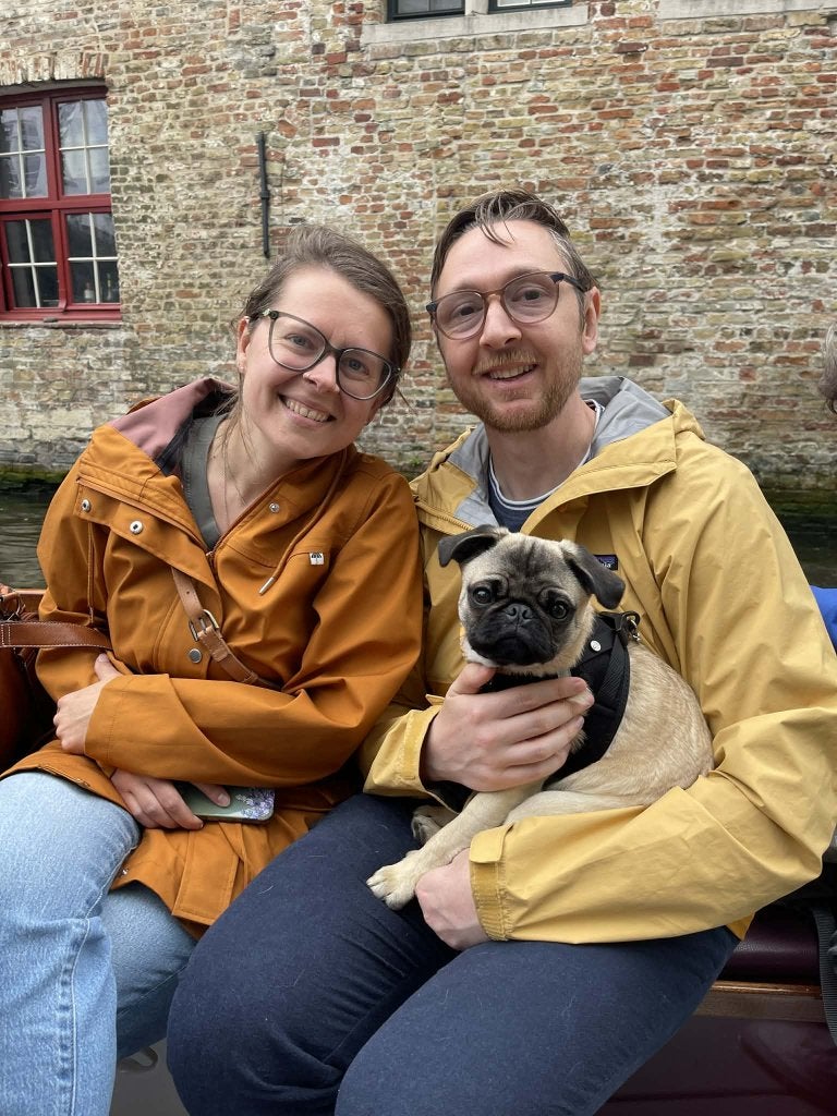 daniel pederson, his wife, and dog, in front of brick building.